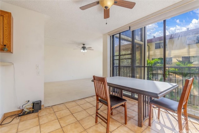 tiled dining space with a wall of windows, a textured ceiling, and ceiling fan