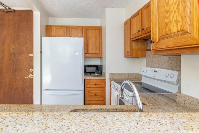 kitchen featuring sink, a textured ceiling, light stone counters, white appliances, and backsplash