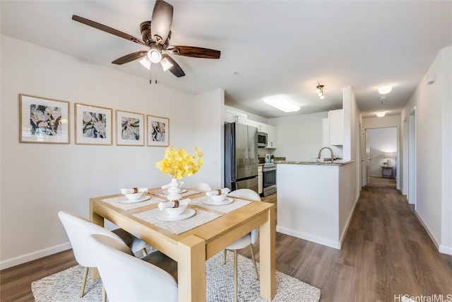 dining area featuring dark wood-type flooring, ceiling fan, and sink