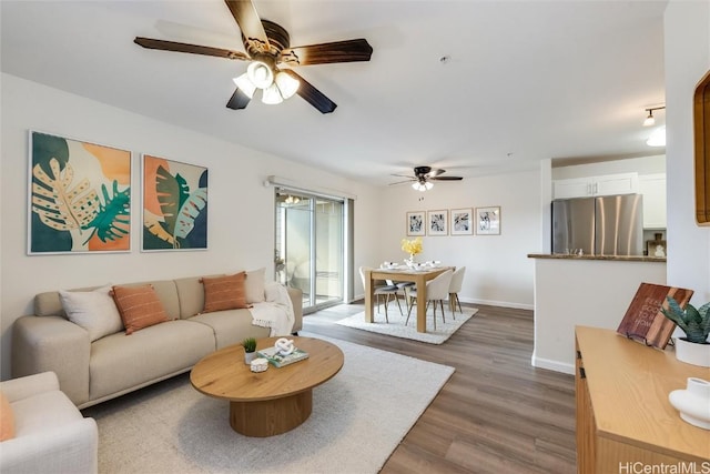 living room featuring ceiling fan and dark hardwood / wood-style floors