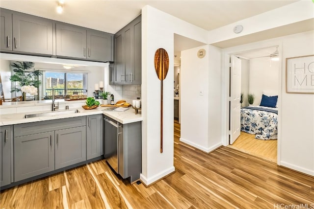 kitchen featuring dishwasher, gray cabinets, light hardwood / wood-style flooring, and tasteful backsplash