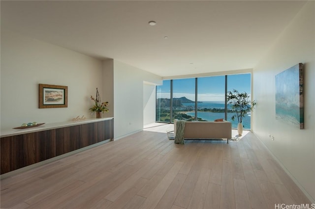 living room featuring a water and mountain view, expansive windows, and light hardwood / wood-style flooring