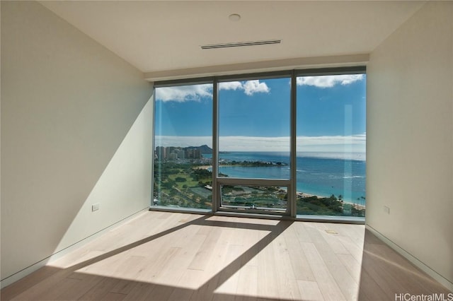 spare room featuring a water view, floor to ceiling windows, and hardwood / wood-style floors