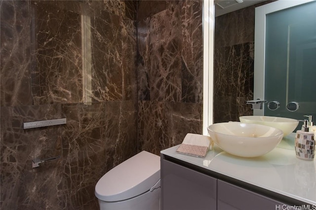 bathroom featuring tile walls, toilet, and vanity