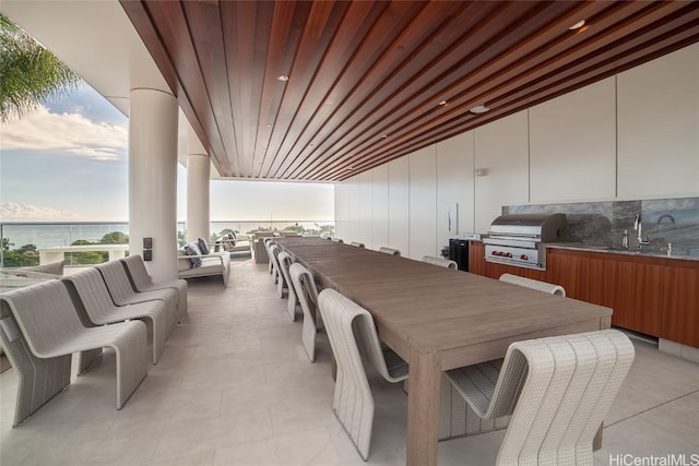 dining room featuring wooden ceiling, a water view, and sink