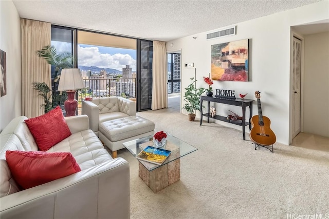 living room featuring visible vents, light colored carpet, expansive windows, a textured ceiling, and a city view