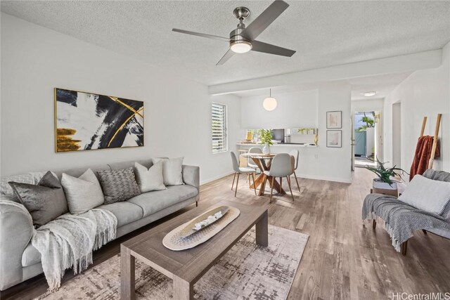 living room with a textured ceiling, ceiling fan, and hardwood / wood-style flooring