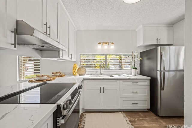 kitchen with stainless steel appliances, white cabinets, sink, and light stone countertops