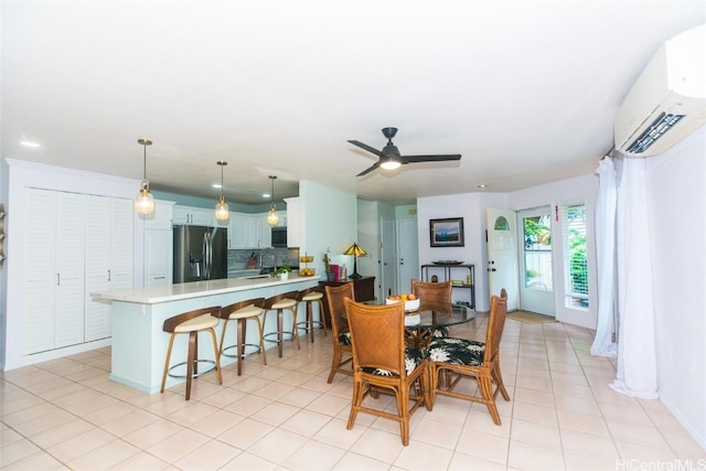 dining area with a wall mounted AC, ceiling fan, and sink