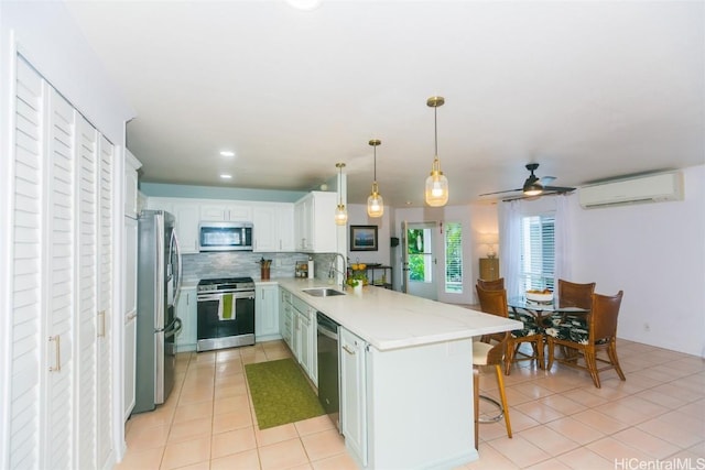 kitchen with sink, a wall unit AC, kitchen peninsula, white cabinets, and appliances with stainless steel finishes