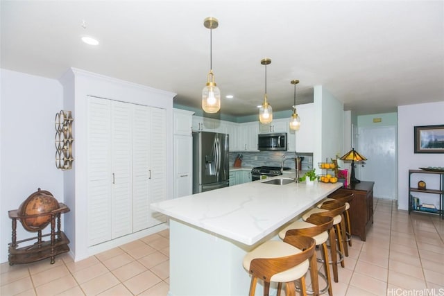 kitchen with backsplash, kitchen peninsula, light tile patterned floors, appliances with stainless steel finishes, and white cabinetry