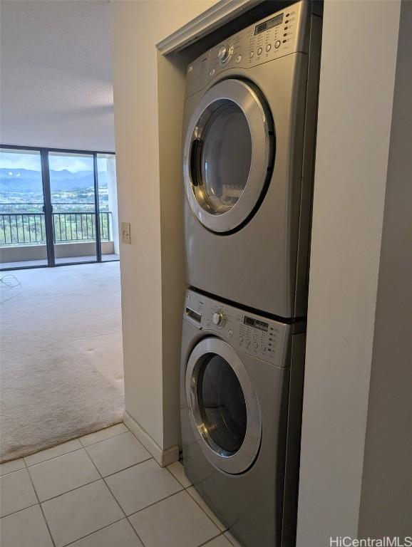 laundry room featuring light carpet and stacked washer / drying machine