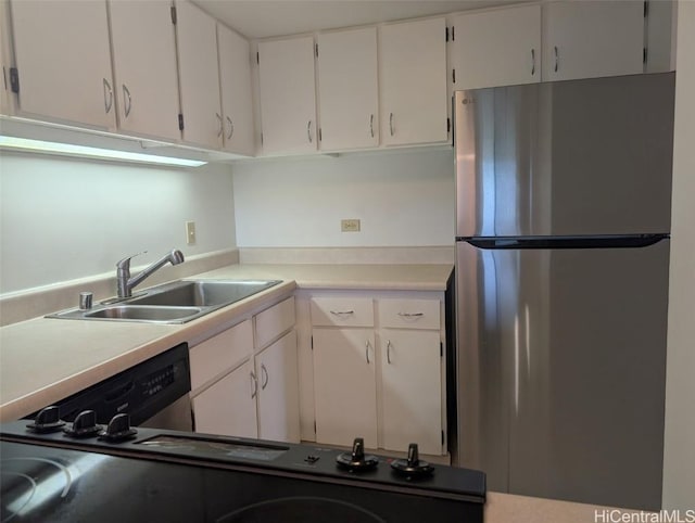 kitchen with white cabinets, stainless steel refrigerator, and sink