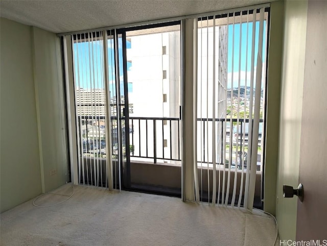 doorway with floor to ceiling windows, carpet, a healthy amount of sunlight, and a textured ceiling