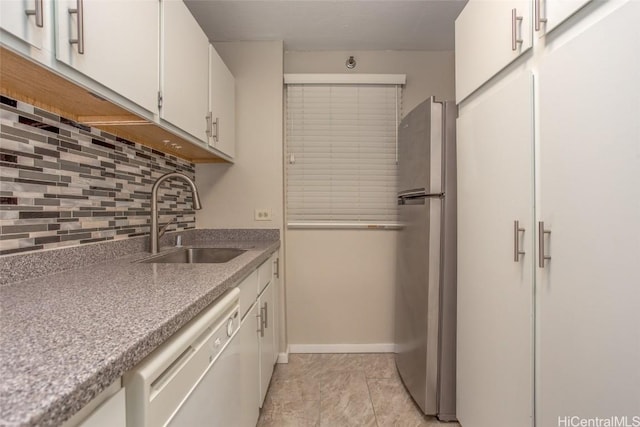 kitchen featuring white dishwasher, white cabinets, sink, stainless steel fridge, and tasteful backsplash