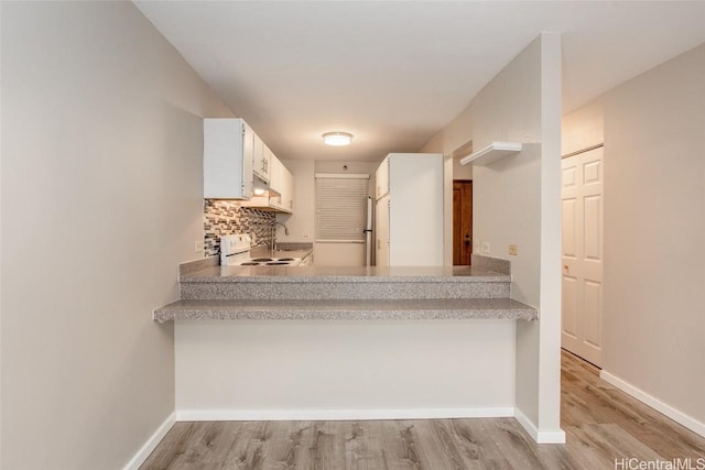 kitchen with light wood-type flooring, backsplash, white cabinetry, and electric stove