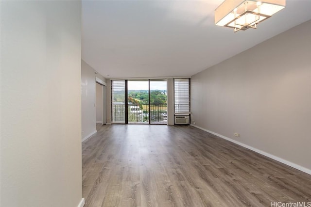 spare room with wood-type flooring, a wall of windows, and a chandelier