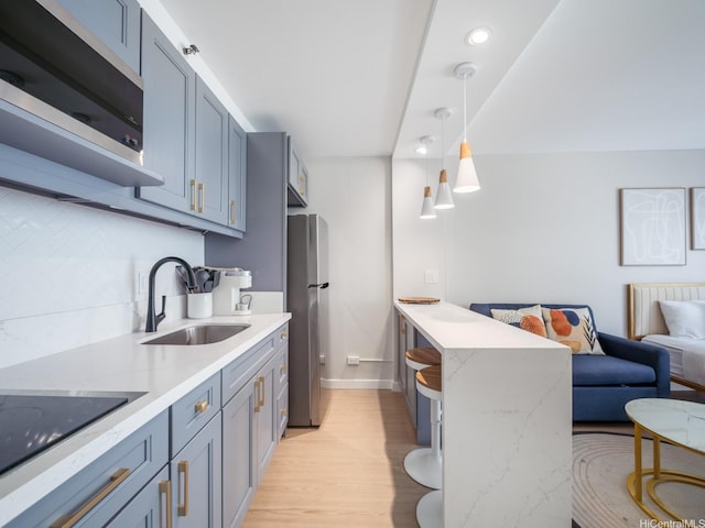 364 Seaside Ave Unit 403, Honolulu, HI 96815 - kitchen featuring a sink, stainless steel appliances, a peninsula, light wood finished floors, and baseboards