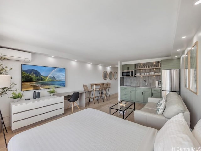 living room with sink, light hardwood / wood-style floors, and a wall mounted air conditioner