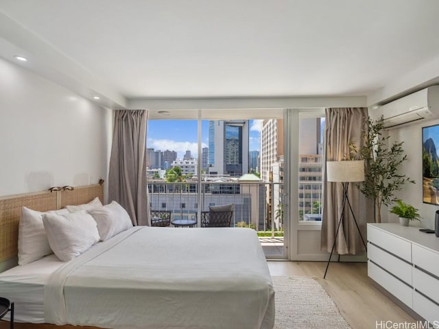 bedroom with an AC wall unit, access to outside, and light hardwood / wood-style flooring