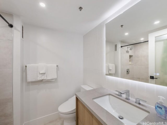 bathroom featuring backsplash, vanity, tiled shower, and toilet