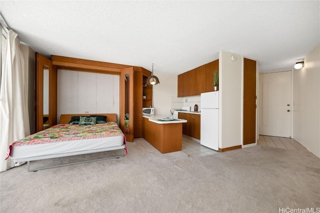 bedroom featuring white refrigerator, light carpet, and a textured ceiling