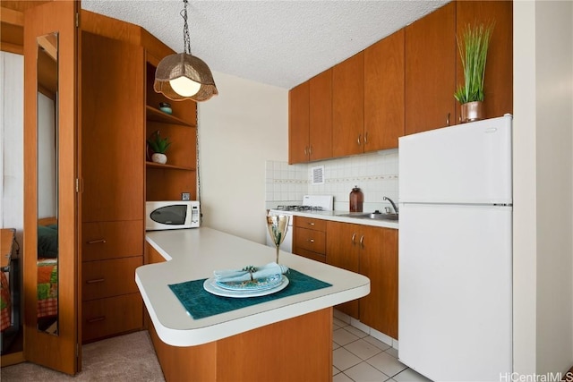 kitchen featuring hanging light fixtures, sink, white appliances, and kitchen peninsula