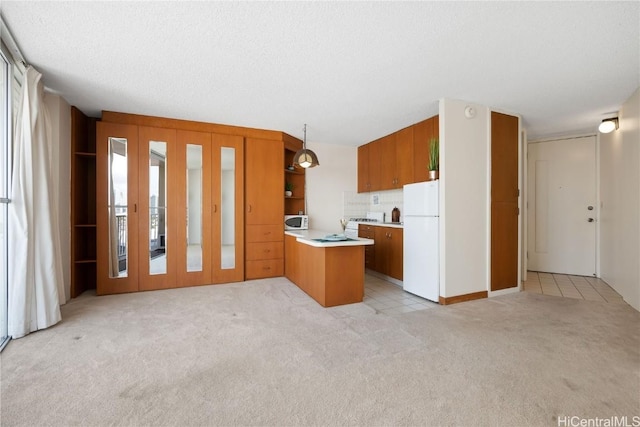 kitchen with decorative light fixtures, a textured ceiling, white refrigerator, kitchen peninsula, and light colored carpet