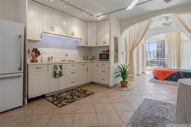 kitchen with white fridge, ceiling fan, backsplash, and white cabinetry