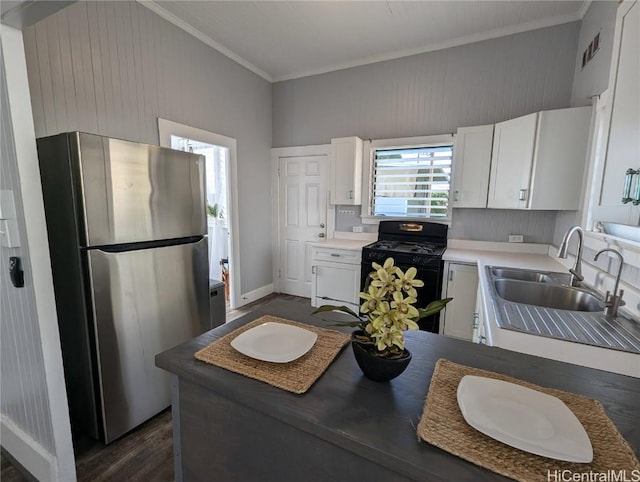 kitchen featuring a sink, white cabinetry, freestanding refrigerator, black gas range oven, and crown molding