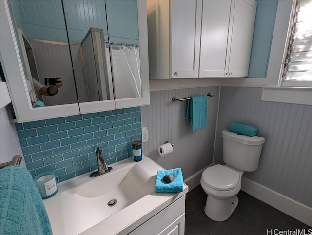 bathroom featuring a wainscoted wall, tasteful backsplash, toilet, vanity, and tile patterned floors