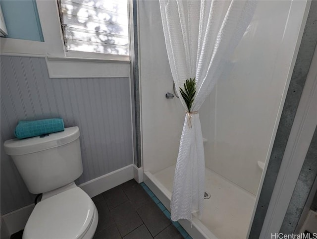 full bathroom with wainscoting, a shower stall, toilet, and tile patterned floors