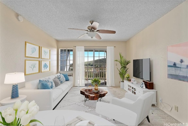 carpeted living room with ceiling fan and a textured ceiling