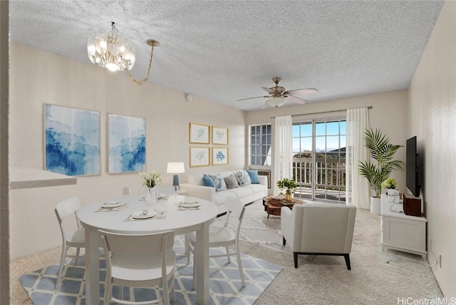 carpeted dining space featuring ceiling fan with notable chandelier and a textured ceiling