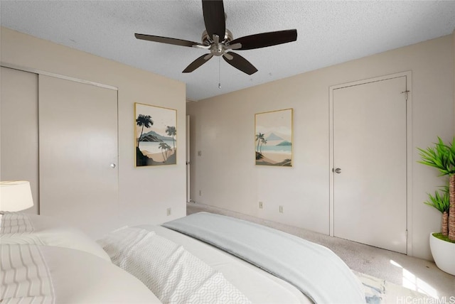 carpeted bedroom featuring ceiling fan and a textured ceiling