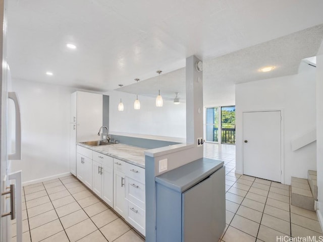 kitchen featuring a sink, a peninsula, white cabinets, light tile patterned flooring, and hanging light fixtures