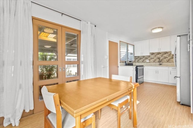 dining area with sink, french doors, and light hardwood / wood-style floors