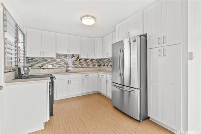 kitchen with white cabinetry, stainless steel appliances, decorative backsplash, sink, and light wood-type flooring