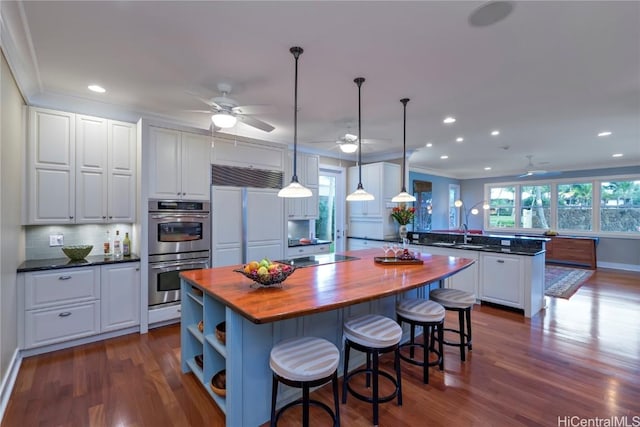 kitchen featuring white cabinetry, wooden counters, paneled built in refrigerator, ornamental molding, and double oven