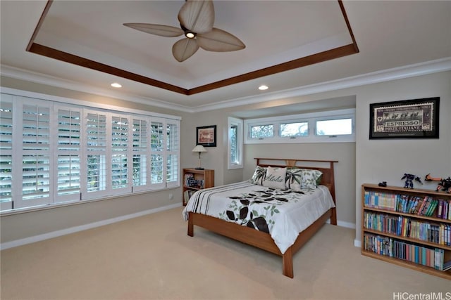 carpeted bedroom with ceiling fan, a tray ceiling, and multiple windows