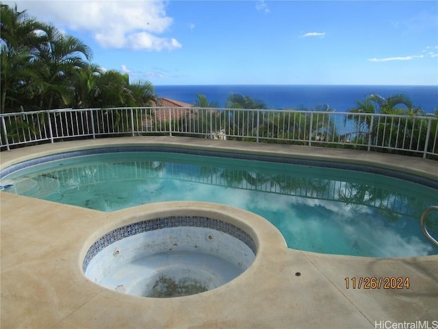 view of pool with an in ground hot tub and a water view