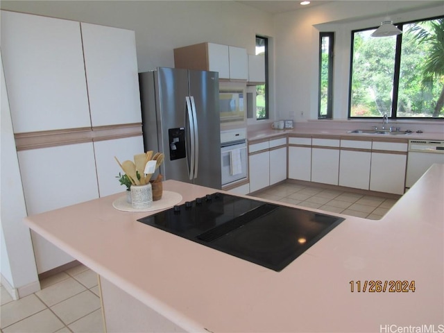 kitchen with sink, white appliances, light tile patterned floors, and white cabinets