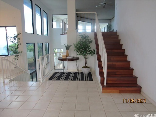 stairway featuring tile patterned floors, a healthy amount of sunlight, and a towering ceiling