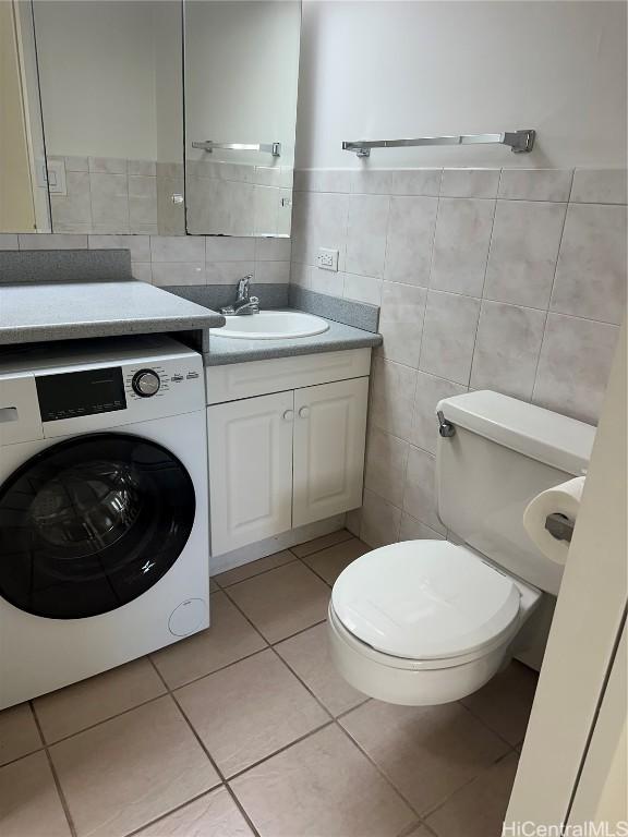 bathroom featuring tile patterned floors, vanity, tile walls, washer / dryer, and toilet