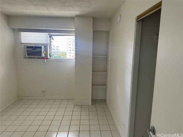 tiled spare room with a textured ceiling and cooling unit