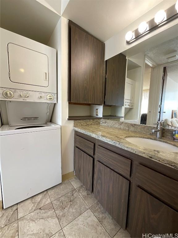 washroom featuring sink and stacked washer / drying machine