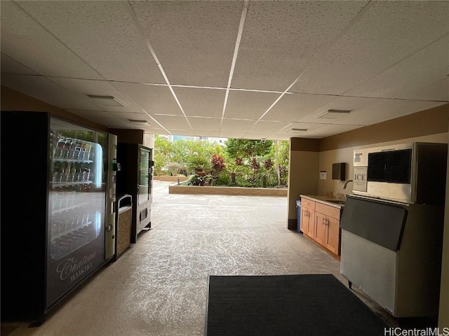 interior space featuring light carpet, light brown cabinetry, a paneled ceiling, sink, and a wall of windows