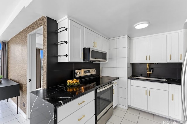 kitchen featuring white cabinetry, sink, dark stone countertops, light tile patterned flooring, and appliances with stainless steel finishes