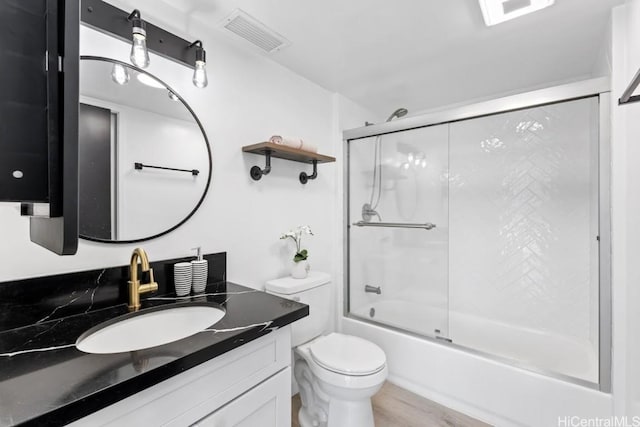 full bathroom with shower / bath combination with glass door, wood-type flooring, vanity, and toilet