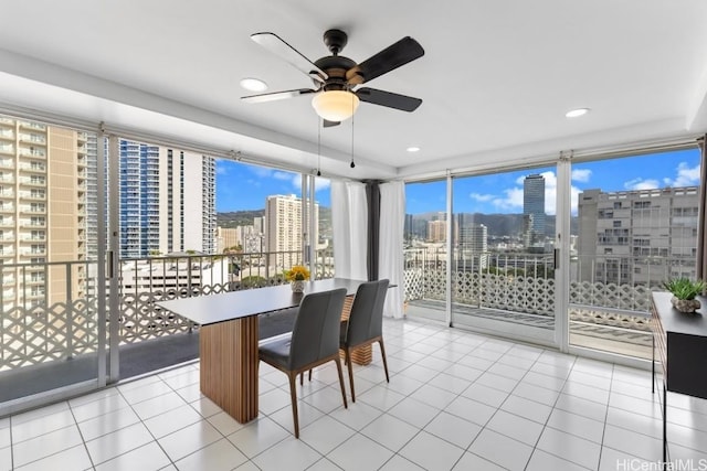 tiled dining room featuring ceiling fan and a wall of windows